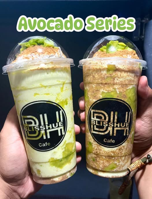Two avocado series frappes with dome lids and graham topping, held side by side