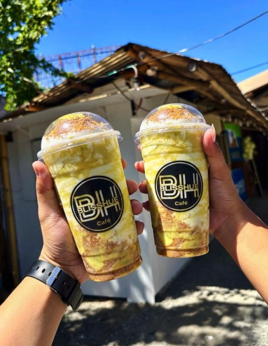 Two green avocado graham frappes held up outside a Blisshue branch